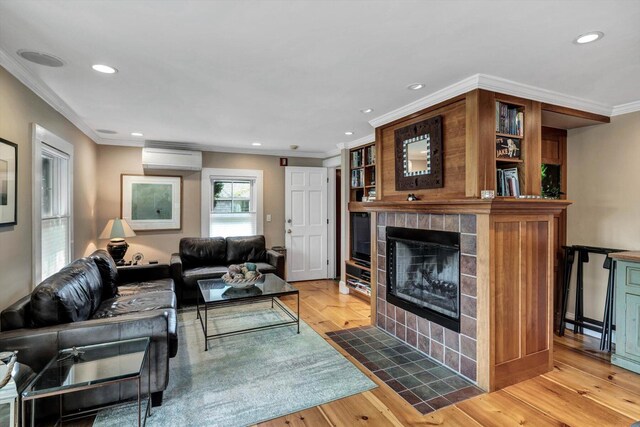 living room featuring a tile fireplace, hardwood / wood-style floors, a wall mounted air conditioner, and ornamental molding