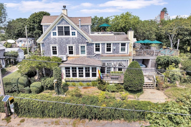 184 Bradford St Unit U1, Provincetown, MA 02657 - back of property with a deck, a chimney, and roof with shingles