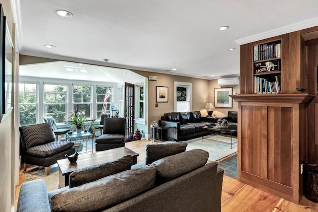 living room featuring ornamental molding, a wall mounted AC, and light wood-type flooring