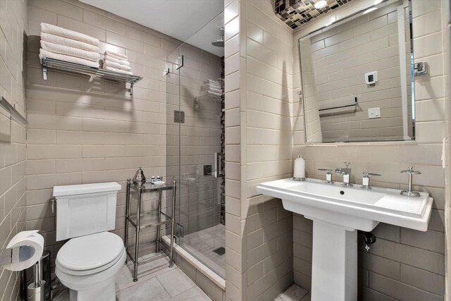 bathroom featuring tile patterned floors, a shower with shower door, tile walls, and toilet