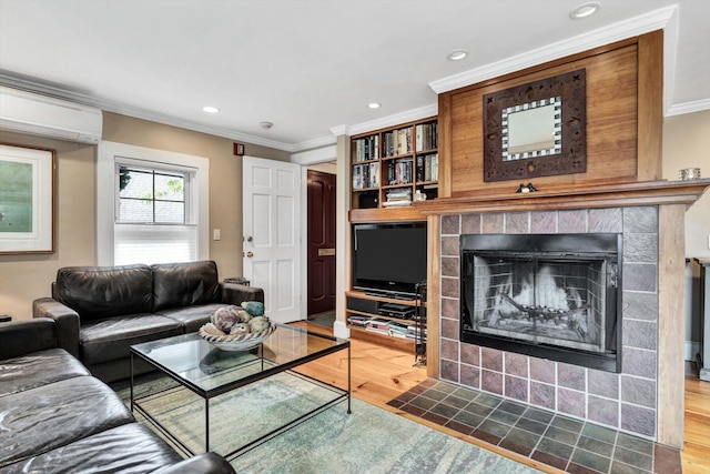 living room featuring a wall mounted air conditioner, crown molding, a tile fireplace, and hardwood / wood-style flooring