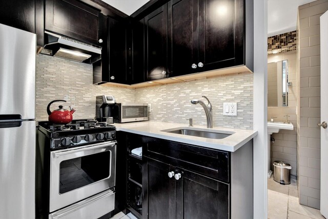 kitchen with appliances with stainless steel finishes, sink, tasteful backsplash, light tile patterned floors, and exhaust hood