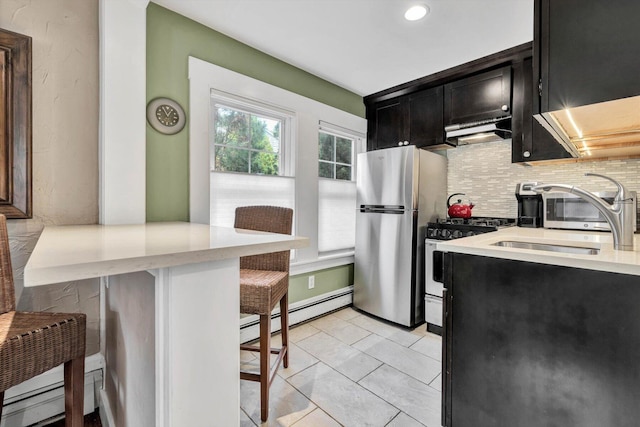 kitchen with a baseboard heating unit, appliances with stainless steel finishes, light tile patterned floors, a breakfast bar, and decorative backsplash