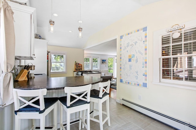 31 Chase St, Dennis Port, MA 02639 - kitchen with a baseboard radiator, lofted ceiling, dark countertops, healthy amount of natural light, and white cabinets