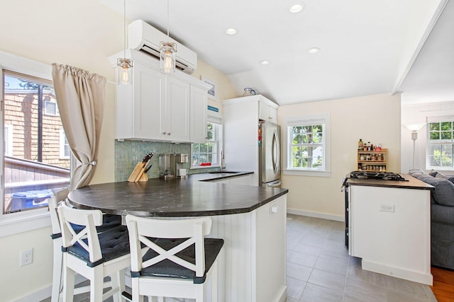 31 Chase St, Dennis Port, MA 02639 - kitchen featuring freestanding refrigerator, dark countertops, an AC wall unit, a peninsula, and a kitchen breakfast bar