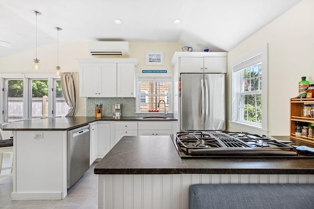31 Chase St, Dennis Port, MA 02639 - kitchen with stainless steel appliances, an AC wall unit, vaulted ceiling, dark countertops, and a peninsula
