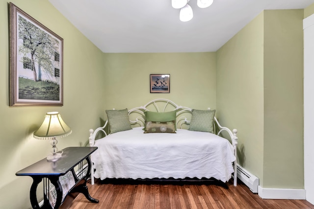 bedroom with a baseboard heating unit and wood-type flooring