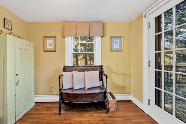 living area with hardwood / wood-style flooring, plenty of natural light, and a baseboard heating unit