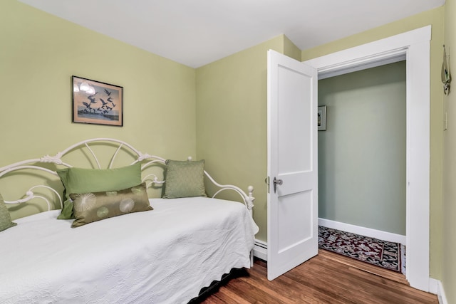 bedroom with baseboard heating and dark wood-type flooring