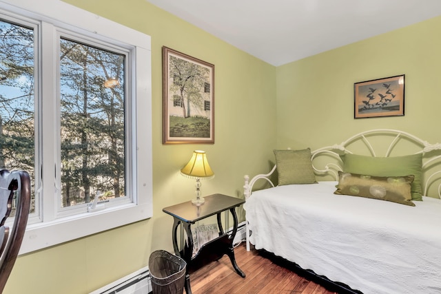 bedroom featuring a baseboard heating unit and wood-type flooring