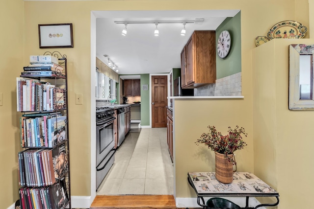 kitchen with tasteful backsplash, dishwasher, light tile patterned flooring, gas range, and sink