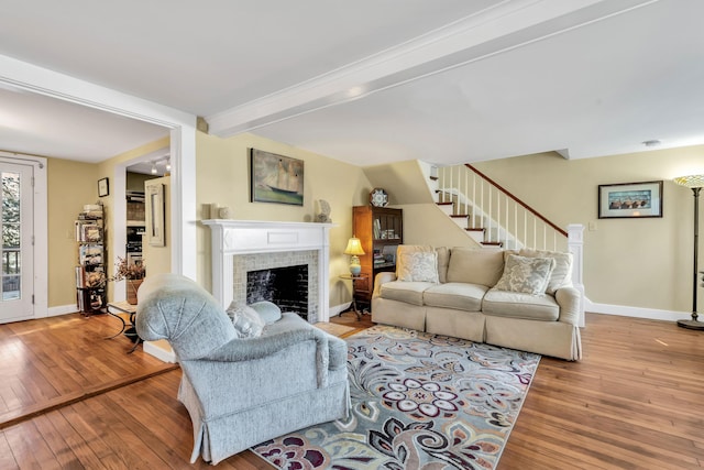 living room featuring light wood-type flooring, a fireplace, and beam ceiling
