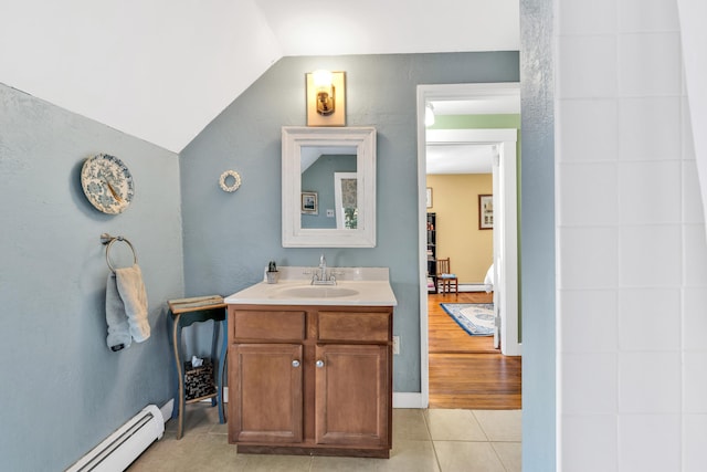 bathroom featuring a baseboard heating unit, vanity, tile patterned flooring, and vaulted ceiling