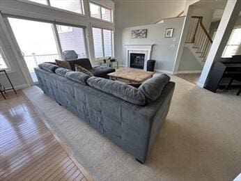 living area with a towering ceiling, baseboards, stairway, and a glass covered fireplace