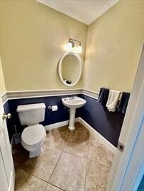 half bath featuring baseboards, toilet, and tile patterned floors