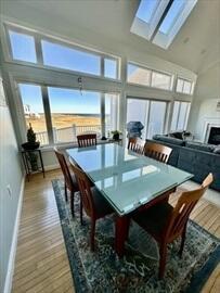 dining space featuring high vaulted ceiling, a skylight, wood finished floors, and baseboards