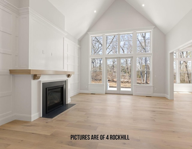 unfurnished living room featuring french doors, a high ceiling, and light hardwood / wood-style flooring