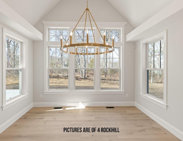 unfurnished dining area featuring light hardwood / wood-style flooring, vaulted ceiling, a chandelier, and a wealth of natural light