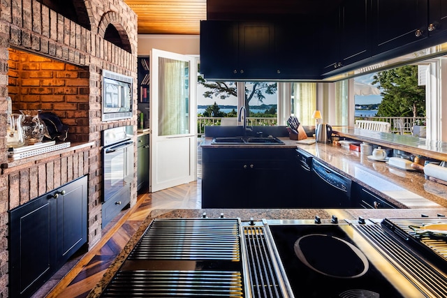 kitchen with stainless steel microwave, black dishwasher, wall oven, sink, and light parquet floors