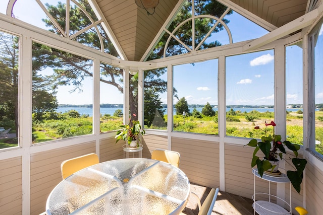 sunroom / solarium featuring a healthy amount of sunlight, a water view, and vaulted ceiling