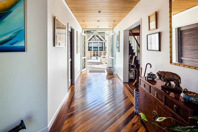 corridor featuring wood ceiling, crown molding, and dark wood-type flooring