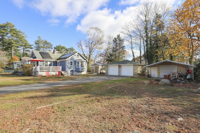 view of front facade with a front yard, a porch, a garage, an outdoor structure, and a carport