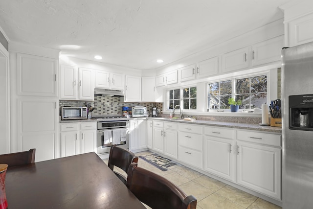 kitchen featuring white cabinets, stainless steel appliances, decorative backsplash, sink, and light tile patterned floors