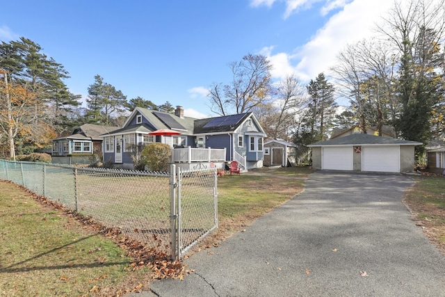 ranch-style home with a garage, an outdoor structure, a front lawn, and solar panels