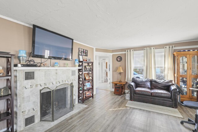 living room featuring hardwood / wood-style flooring, a tile fireplace, and ornamental molding