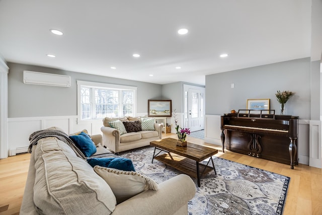 living area with wood finished floors, wainscoting, baseboard heating, and a wall mounted AC