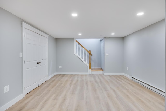 finished basement with recessed lighting, stairs, light wood-style floors, and a baseboard radiator