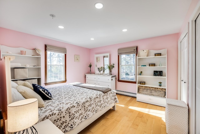 bedroom featuring recessed lighting, multiple windows, baseboard heating, and light wood-style flooring