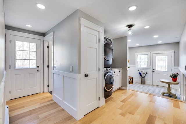 washroom featuring recessed lighting, cabinet space, light wood-style floors, and stacked washing maching and dryer