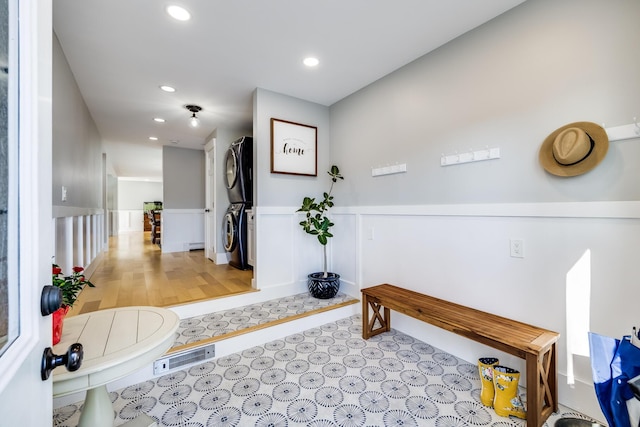 hallway with recessed lighting, a wainscoted wall, and stacked washer / dryer