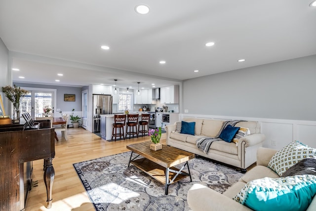 living room with recessed lighting, a wainscoted wall, plenty of natural light, and light wood finished floors