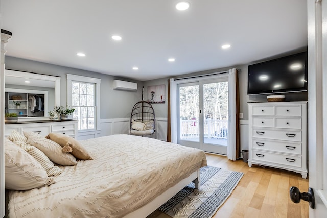 bedroom featuring a wainscoted wall, recessed lighting, access to exterior, light wood-style floors, and a wall mounted air conditioner