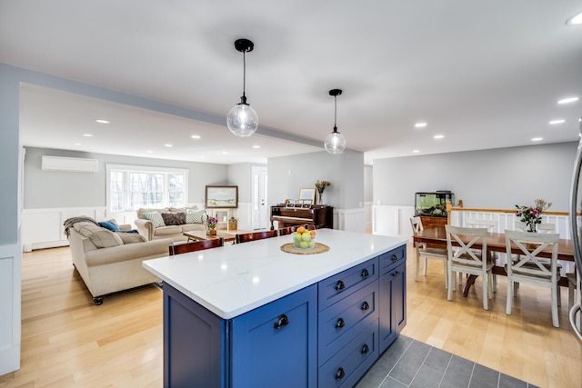 kitchen with light wood-type flooring, a wainscoted wall, a kitchen island, and a wall mounted AC