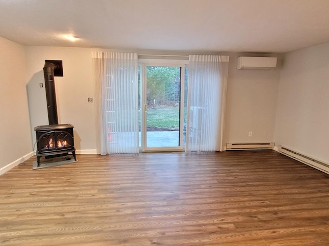 unfurnished living room with a wood stove, wood finished floors, baseboards, a wall mounted AC, and a baseboard radiator