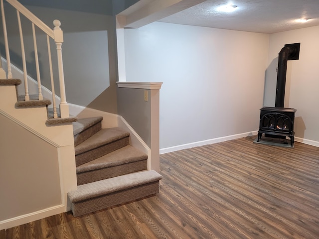 stairs with baseboards, a wood stove, and wood finished floors