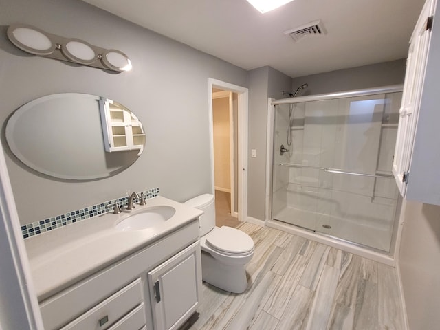 full bathroom with visible vents, a shower stall, wood finished floors, vanity, and toilet