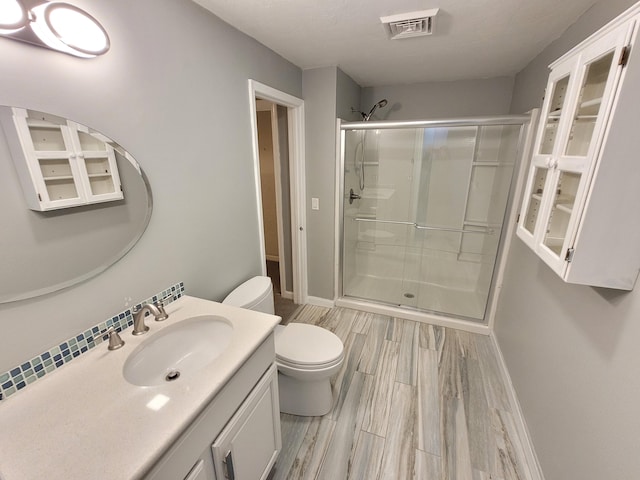full bath featuring visible vents, vanity, wood finished floors, toilet, and a shower stall