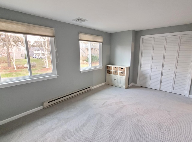 unfurnished bedroom with a baseboard heating unit, light carpet, visible vents, and a closet