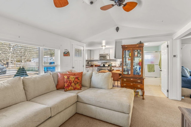 living area with vaulted ceiling, a ceiling fan, and light colored carpet