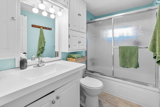 bathroom featuring enclosed tub / shower combo, vanity, toilet, and tile patterned floors