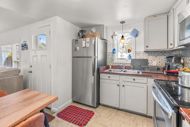 kitchen featuring stainless steel appliances, a wealth of natural light, a sink, and backsplash