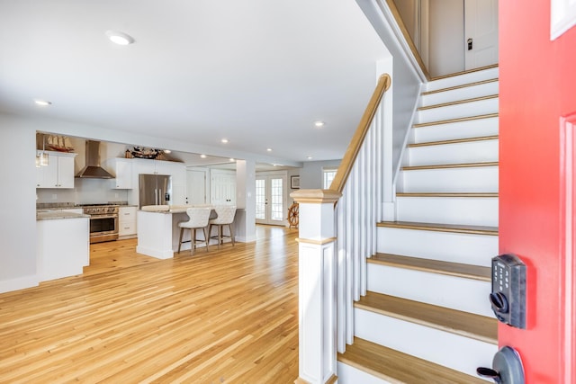 stairway with hardwood / wood-style flooring and french doors