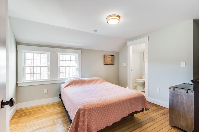 bedroom featuring lofted ceiling, light hardwood / wood-style flooring, and ensuite bathroom