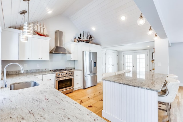 kitchen with appliances with stainless steel finishes, wall chimney range hood, white cabinets, sink, and light stone counters