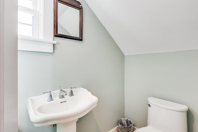 bathroom featuring sink, toilet, and vaulted ceiling