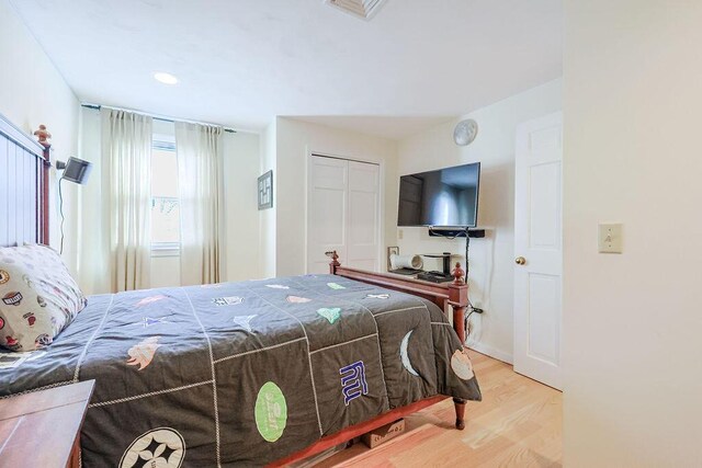 bedroom with a closet, visible vents, and wood finished floors